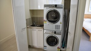 Un espace buanderie compact comprenant un lave-linge, un sèche-linge et un petit évier.