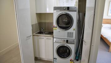 A compact laundry room with a washing machine, dryer, and a small sink.