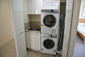 A compact laundry area with a washing machine, dryer, and a small sink.
