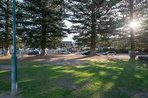 A park with trees, a picnic table, and a building in the background.
