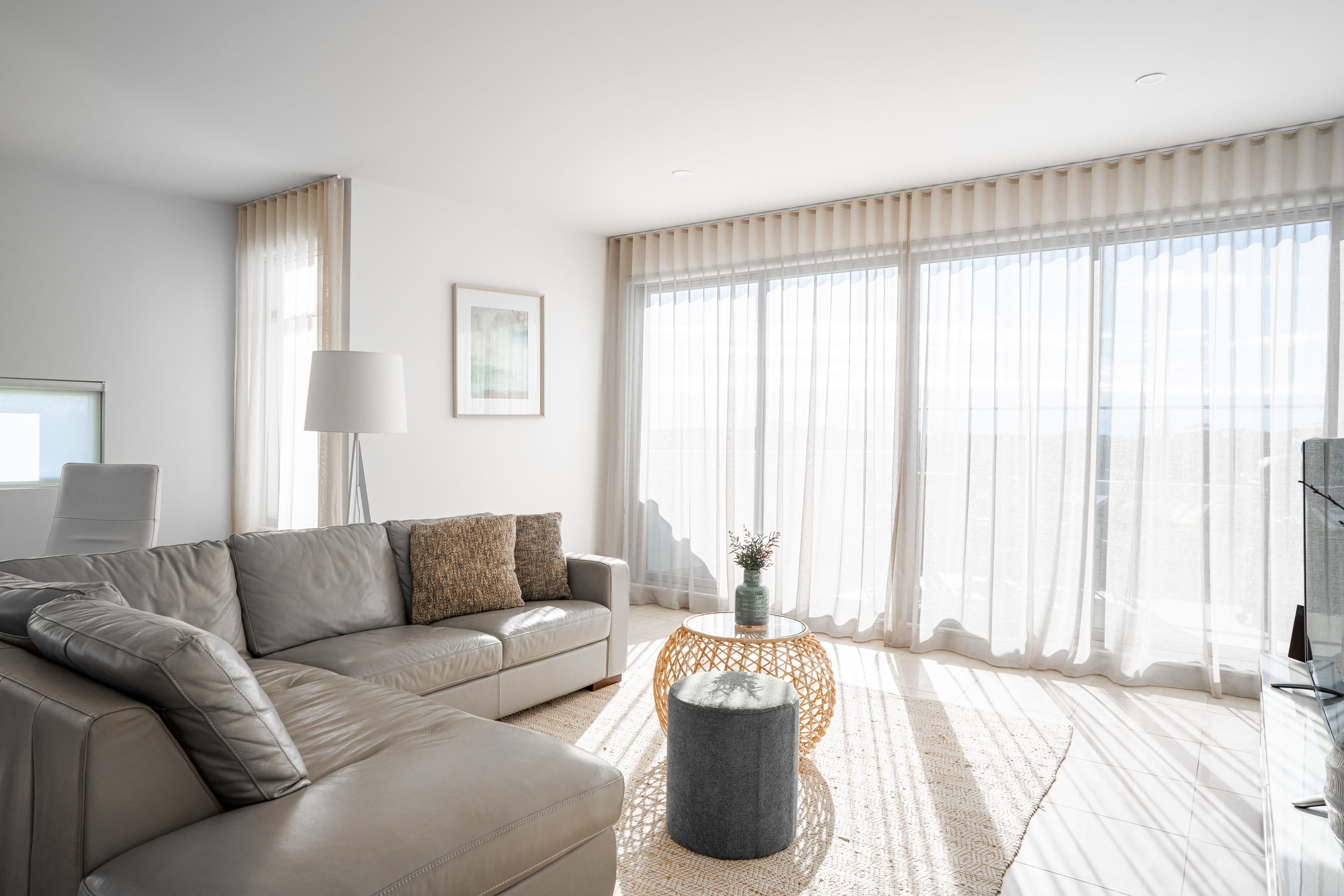A modern living room with a sofa, a round coffee table, and sheer curtains.