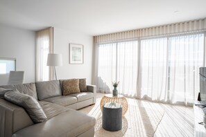 Ein modernes Wohnzimmer mit einer Couch, einem runden Couchtisch und transparenten Vorhängen.