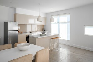 A modern kitchen with a central island, white cabinetry, and pendant lighting.