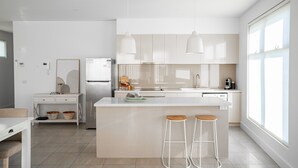 Une cuisine moderne dotée d’un îlot central, de tabourets de bar et de luminaires suspendus.