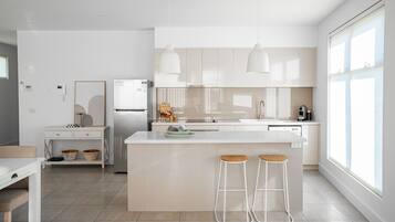 A modern kitchen with a central island, bar stools, and pendant lighting.