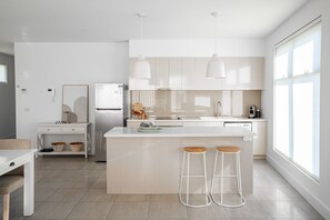 A modern kitchen with a central island, bar stools, and pendant lighting.