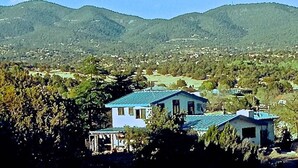 A house with a blue roof, surrounded by greenery and hills in the background.