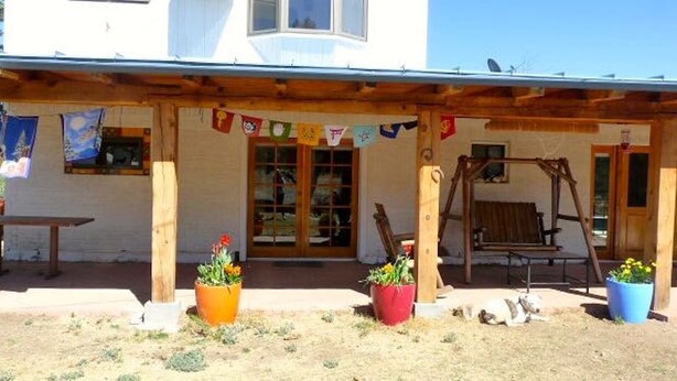 A wooden porch with a swing set and potted plants.