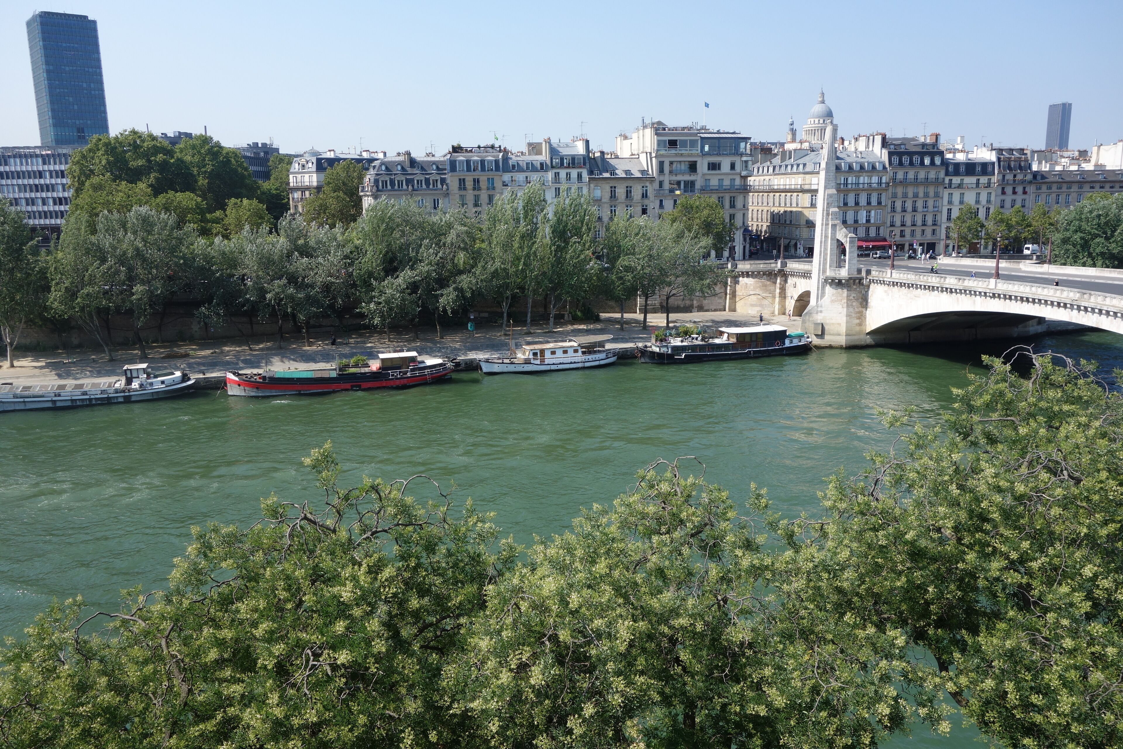 A river with boats, a bridge, and buildings in the background.