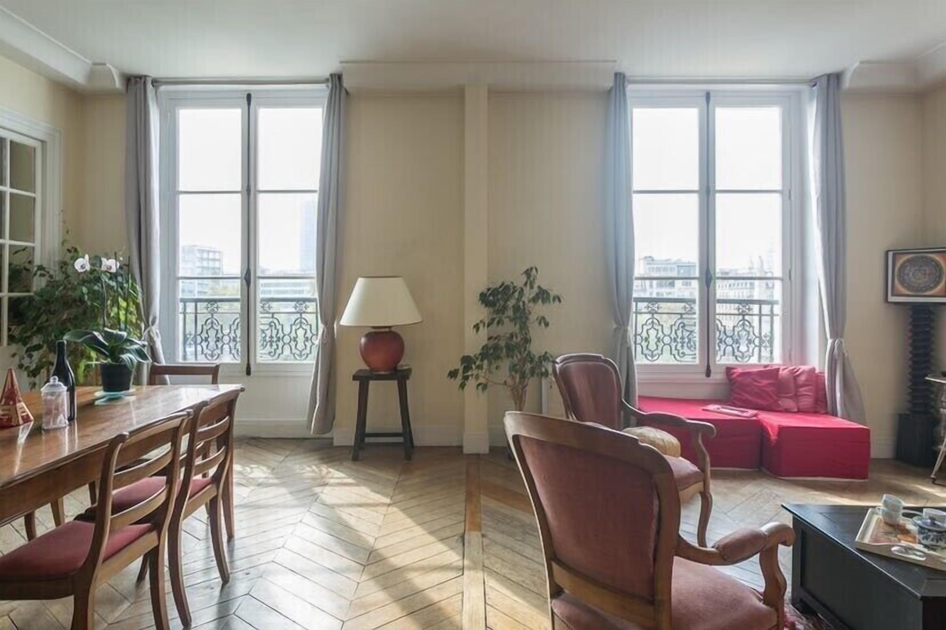 A living room with a wooden dining table, chairs, a sofa, a TV, and a potted plant.