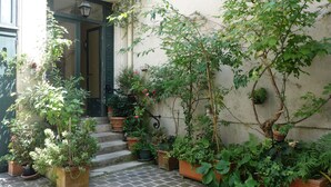 A courtyard with potted plants, a staircase, and a door leading to a building. - Paris-sur-seine-chez-caroline (Paris)