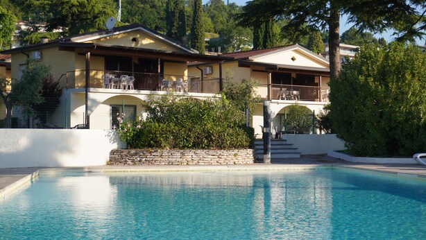 A hotel with a pool, balconies, and a stone wall. - Three-room villa direct to the beach, 6 beds garden pool  (Manerba del Garda)