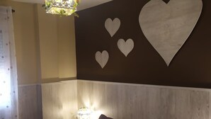 Ein Schlafzimmer mit einem Bett, Wanddekoration, einer Chandelüster und einem Nachttisch mit Lampe.