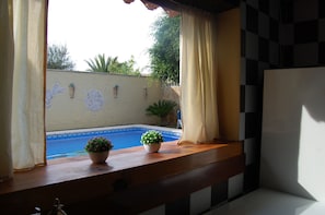 Ein Zimmer mit Blick auf einen Swimmingpool, einer Holzbank und einer karierten Wand.