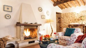 Un salon chaleureux avec une cheminée, un canapé à motifs floraux et un mur en pierre.
