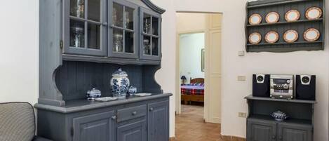 Un salon avec un meuble de couleur bleu foncé, un vase bleu et blanc, et une étagère avec des haut-parleurs.