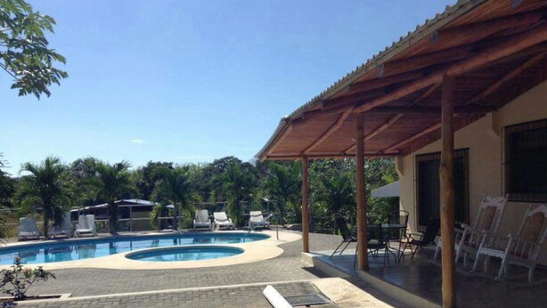 Ein Poolbereich mit Liegestühlen und einer überdachten Terrasse.