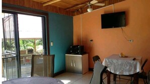 Ein Essbereich mit Tisch und Stühlen, einem an der Wand befestigten Fernseher und einer Schiebetür zu einem Außenbereich.