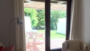 A room with a bed, a chair, a sofa, and a large sliding glass door leading to an outdoor patio with a table and chairs. - 2 Bedrooms, Beach at 300m, Parking (Albufeira)