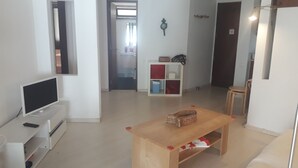 A living room with a TV, a wooden table, a bookshelf, and a door. - 2 Bedrooms, Beach at 300m, Parking (Albufeira)