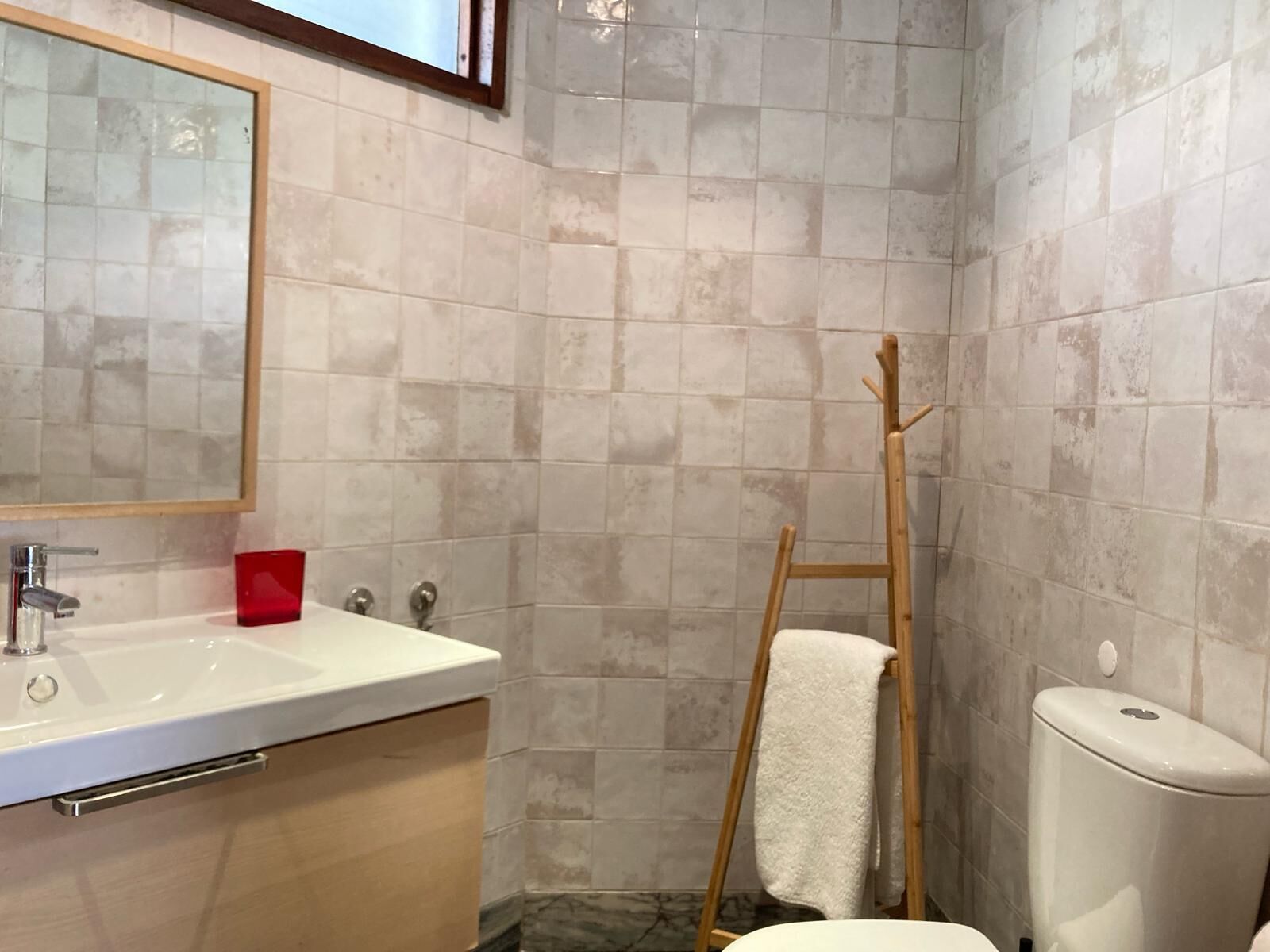 Un bany amb un lavabo blanc, mirall i vàter.