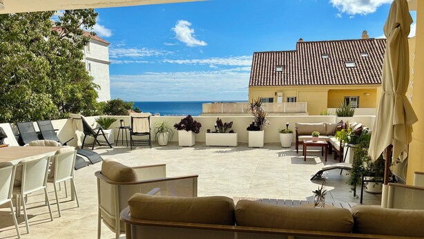 A sunlit outdoor patio with seating, potted plants, and a view of the sea. - Large 3 bedrooms apartment close to marina (Estepona)