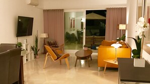 A modern living room with a sofa, chairs, a coffee table, and a TV. - Large 3 bedrooms apartment close to marina (Estepona)