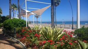 A coastal promenade with a white canopy structure, palm trees, and a beach in the background. - Large 3 bedrooms apartment close to marina (Estepona)