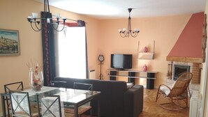 Una sala de estar con televisor, sofá, mesa de comedor, sillas y chimenea.