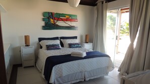Een slaapkamer met een bed, nachtkastjes, een kunstwerk aan de muur en uitzicht door een raam.