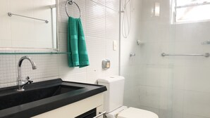 A bathroom with a white toilet, a black sink, a glass shower enclosure, and a green towel hanging on a metal towel ring. - House nearby SEA with pool in Balneário Camboriú  (Pioneiros)