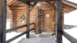 A log cabin with a wooden door, a small window, and a metal door handle.