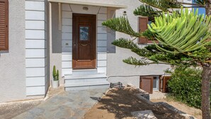 Un edificio con puerta de madera, escalones de piedra y una pequeña planta en maceta.