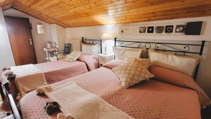 Een slaapkamer met twee bedden, een houten plafond, wanddecoratie en een nachtkastje met een lamp.