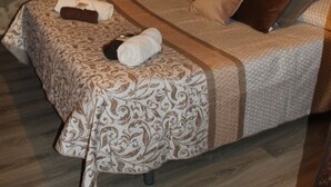 Un dormitorio acogedor con pared de piedra, techo de madera y cama con ropa de cama estampada.