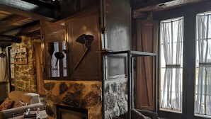 Un interior rústico con chimenea de piedra, leña y una zona de estar acogedora.