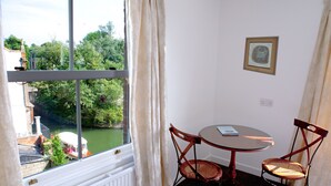 Une pièce avec vue sur une rivière, une table avec des chaises et un tableau encadré au mur.