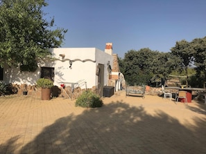 Ein Innenhof mit einem weißen Gebäude, einer Steinsäule und einer Sitzecke mit Stühlen und einem Tisch.