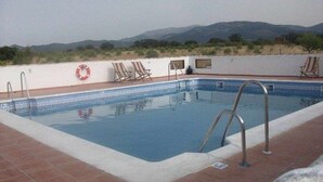 A rectangular swimming pool with a tiled deck, metal pool ladder, and a lifebuoy.