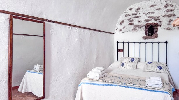 A bedroom with a bed, a large mirror, and a unique wall decoration.