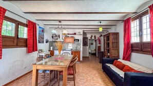 A spacious living area with a dining table, sofa, and kitchen in the background.
