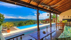 Un espace extérieur abrité, doté d’une piscine, de mobilier en bois et offrant une vue sur le paysage.