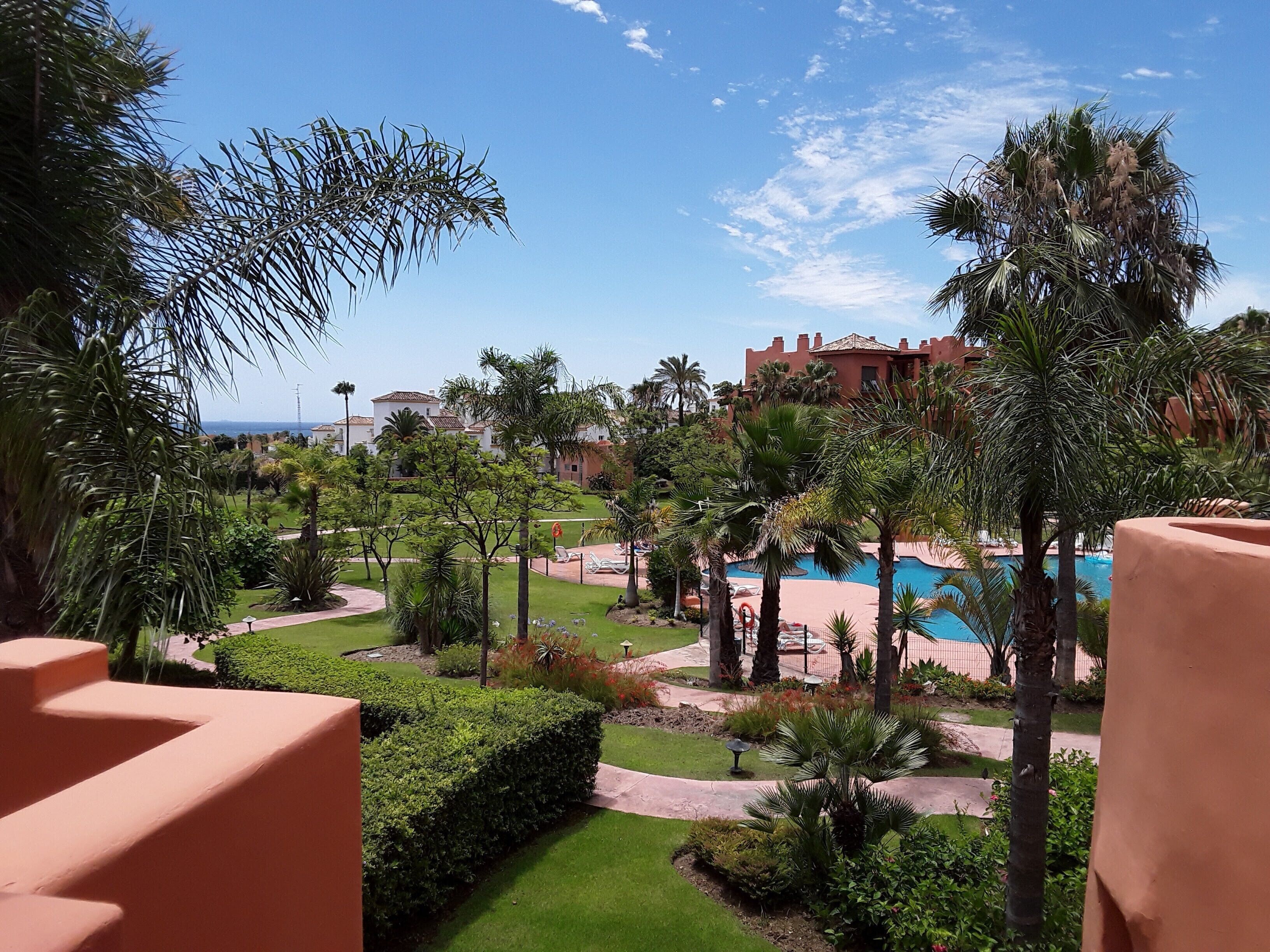 Um resort com piscina, palmeiras e vista para o oceano.