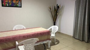 Een eetruimte met een tafel, stoelen, een schilderij aan de muur en een gordijn.