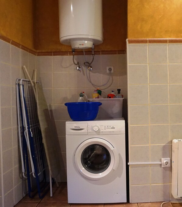 A compact laundry area with a washing machine, a drying rack, and a blue basin on top. - Holiday House in Asturias (Asturias)