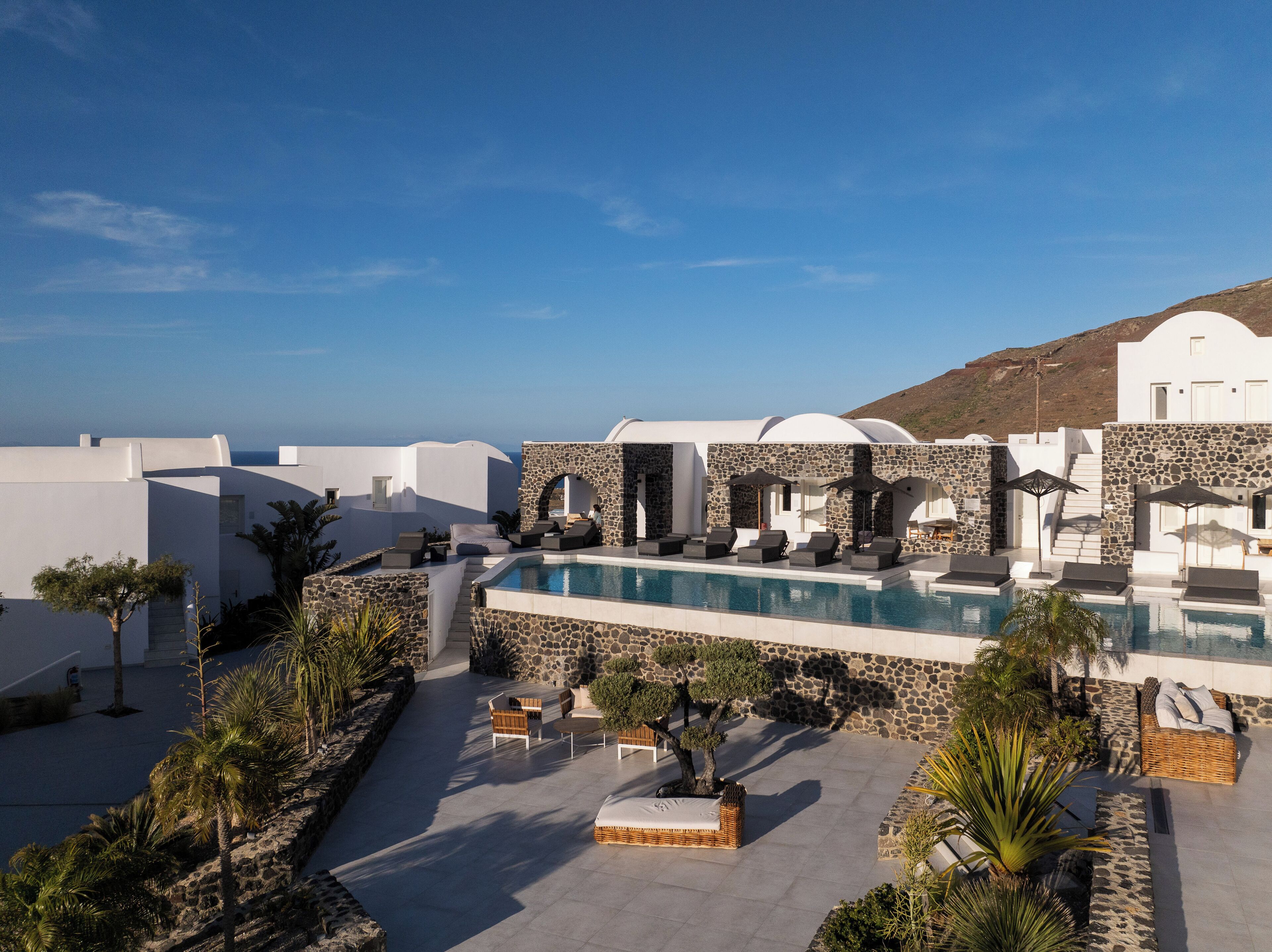 A resort with a pool, outdoor seating, and a view of the sea.