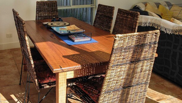 A dining area with a wooden table, wicker chairs, and a blue placemat.