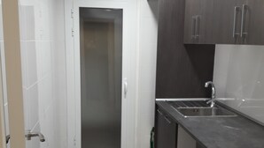 Eine moderne Küche mit dunklen Schränken, einer Edelstahl-Spüle und einer weißen Tür.