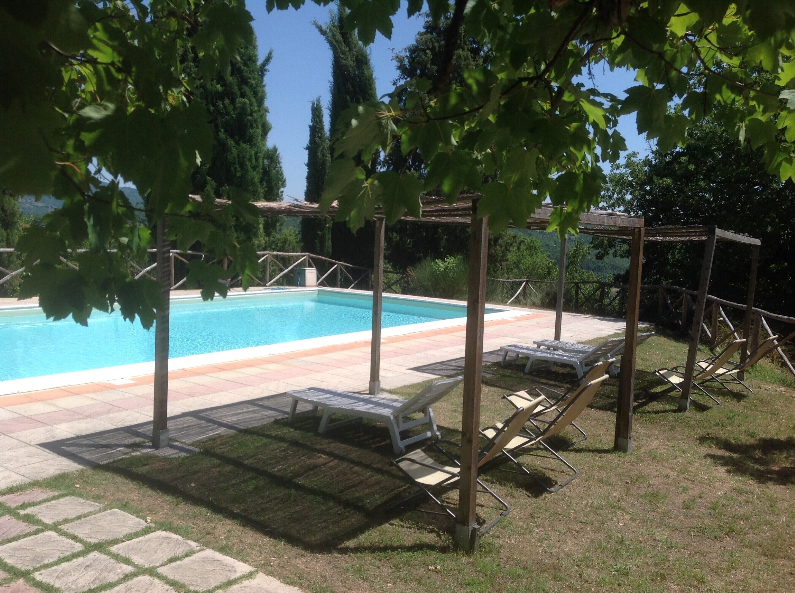 A swimming pool with lounge chairs and a pergola structure.