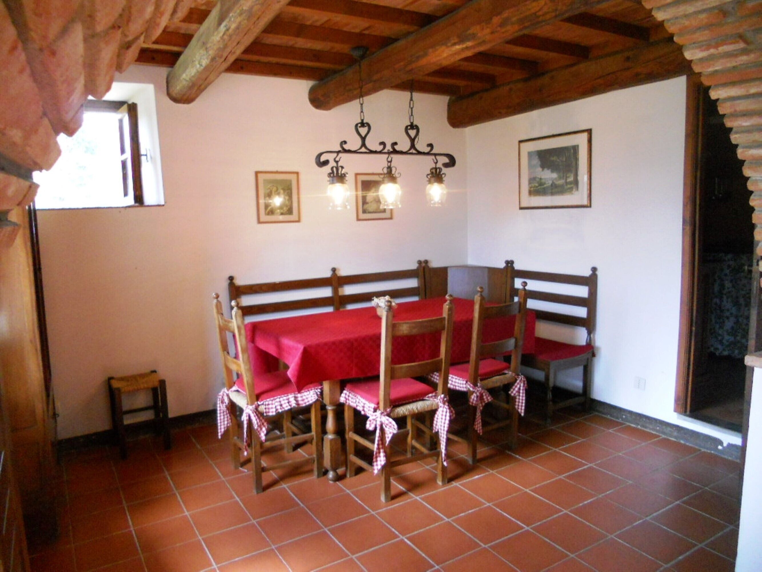 Un comedor rústico con un banco y una mesa de madera dispuesta para cuatro personas, con manteles a cuadros.